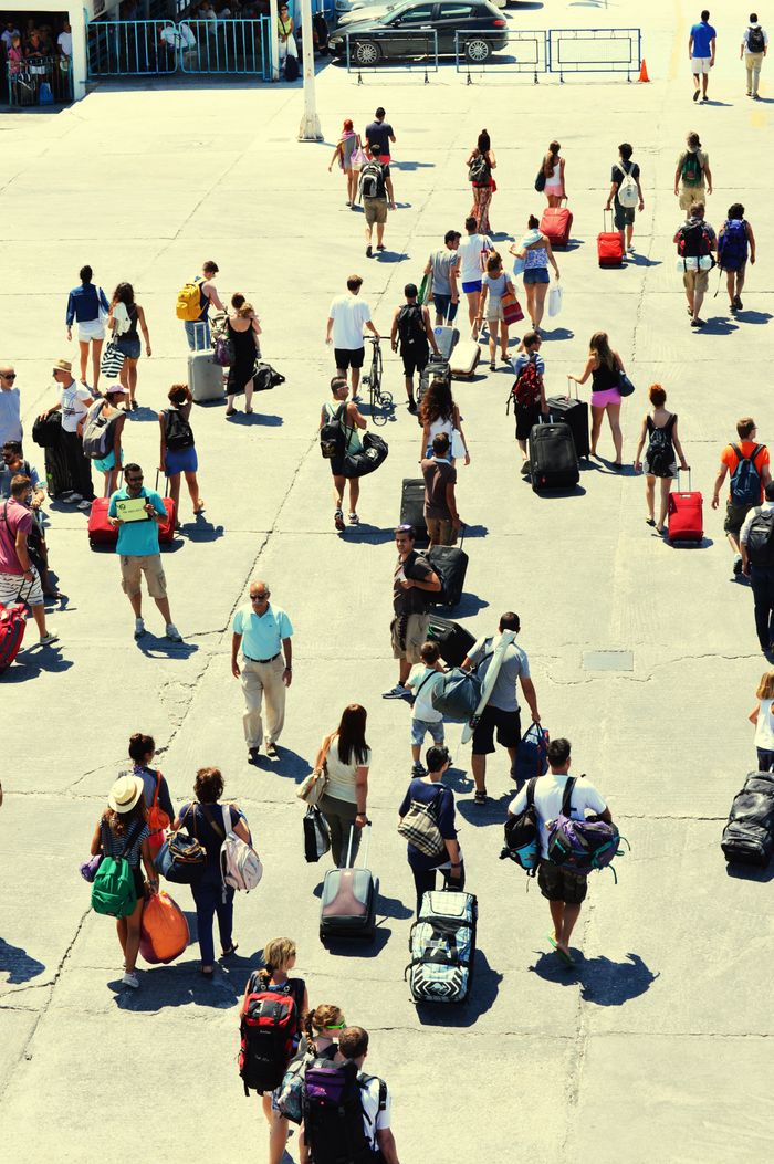 Crowd of tourists with luggage at Paros ferry port, Greece on a sunny day.