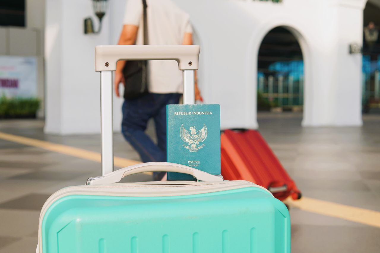Traveler arrives at Yogyakarta airport, Indonesia with luggage and Indonesian passport in focus.